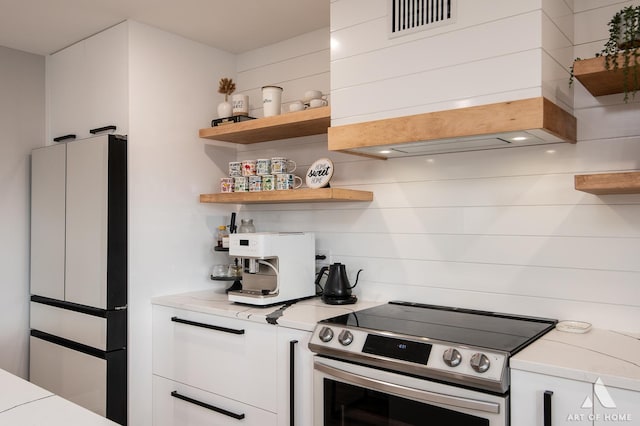 kitchen with white cabinetry, open shelves, premium range hood, and stainless steel range with electric stovetop