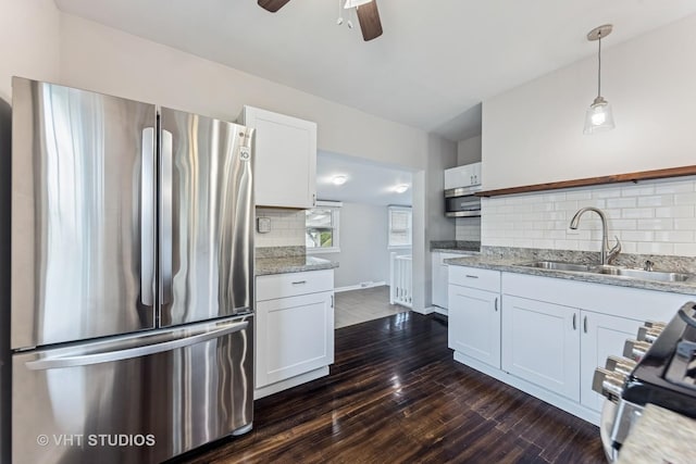 kitchen featuring white cabinets, appliances with stainless steel finishes, a sink, a ceiling fan, and tasteful backsplash