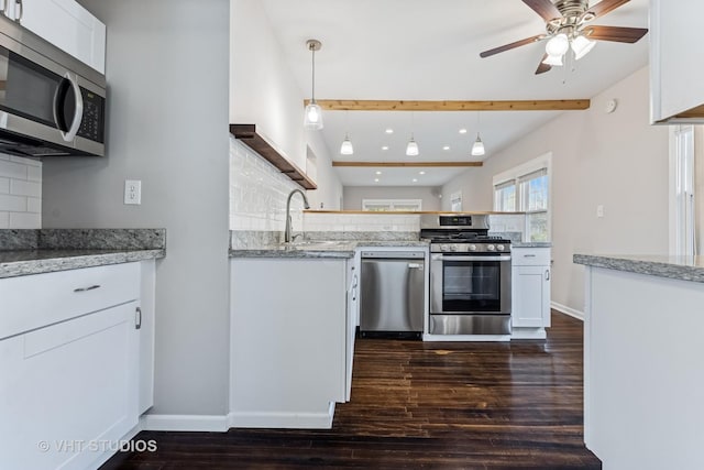 kitchen with a sink, appliances with stainless steel finishes, backsplash, and dark wood-style flooring
