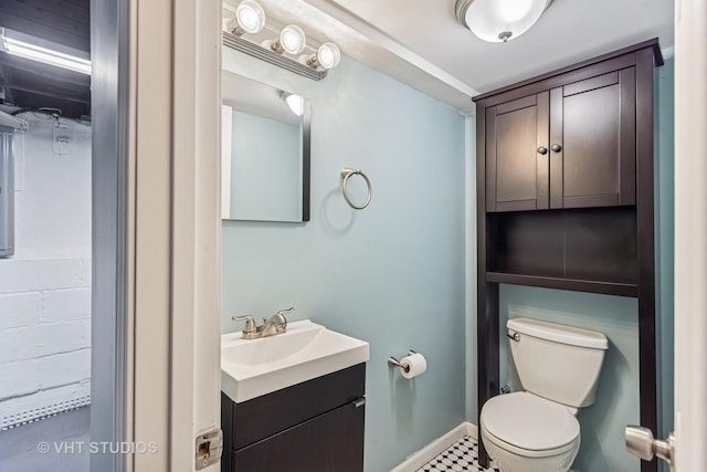 half bathroom featuring toilet, baseboards, and vanity
