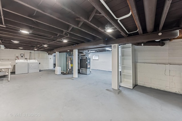 basement with a sink, heating unit, gas water heater, and washer and clothes dryer