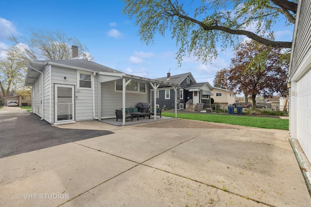 rear view of property with a patio, a lawn, and a chimney