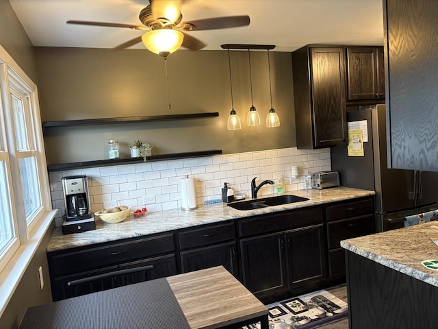 kitchen with open shelves, backsplash, freestanding refrigerator, and a sink