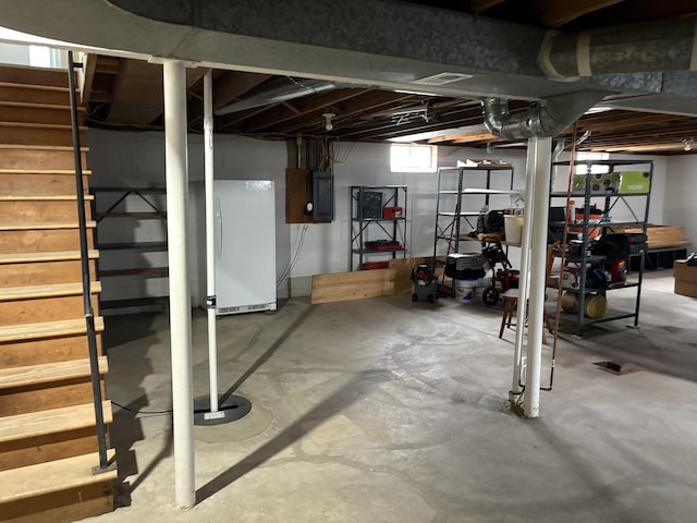 below grade area featuring stairway, electric panel, and freestanding refrigerator
