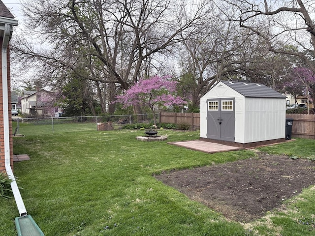 view of yard featuring a storage unit, a fire pit, an outbuilding, and a fenced backyard