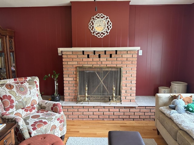 living room with a brick fireplace and wood finished floors