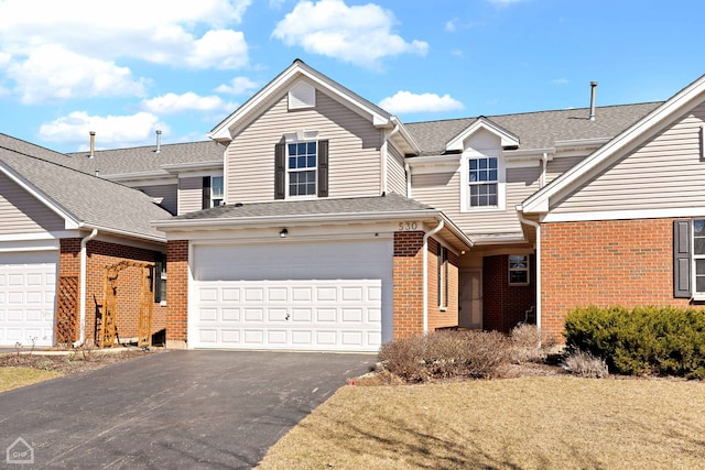 traditional-style home with brick siding, aphalt driveway, and roof with shingles