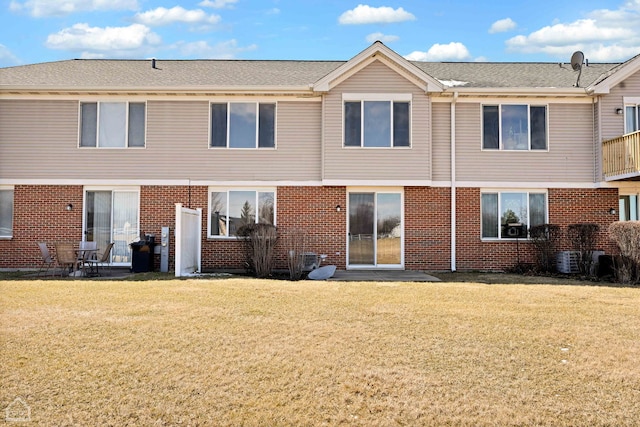 back of property featuring a yard and brick siding