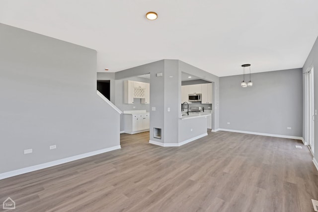 unfurnished living room featuring a sink, visible vents, baseboards, recessed lighting, and light wood finished floors