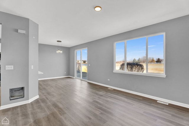 unfurnished living room featuring baseboards, visible vents, and wood finished floors