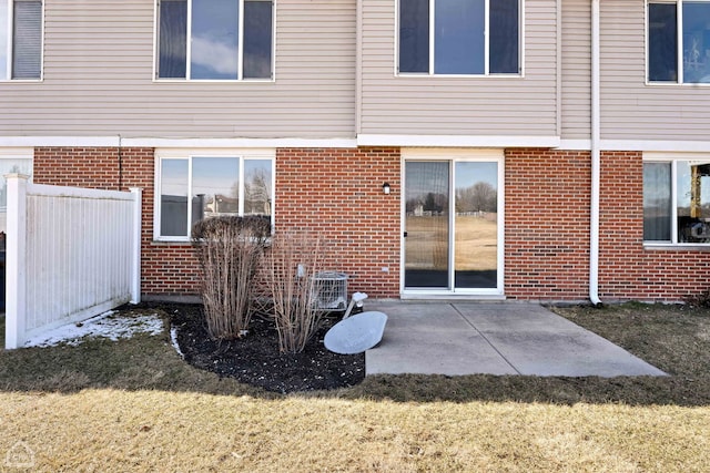 back of property with a patio, brick siding, fence, and a yard