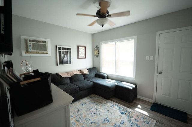 living area featuring ceiling fan, a wall unit AC, light wood-style flooring, and baseboards