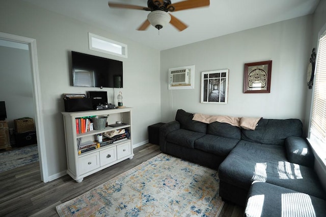 living room with a ceiling fan, a wall mounted AC, wood finished floors, and baseboards