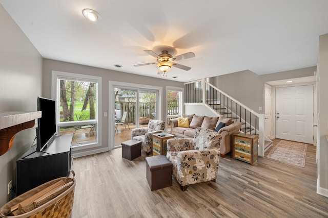 living area featuring wood finished floors, a healthy amount of sunlight, and stairs