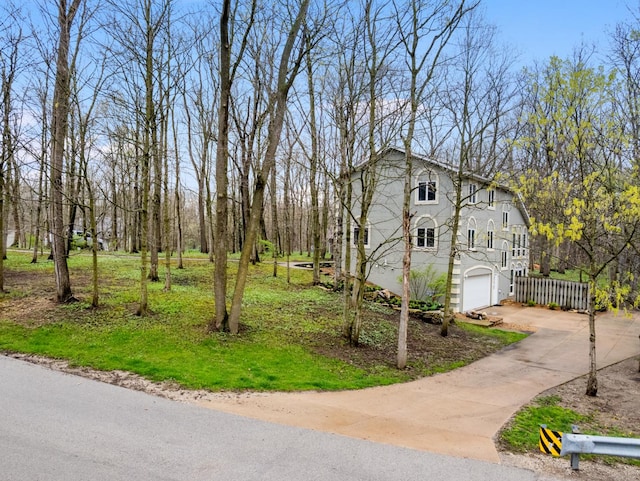 view of side of home with a garage, fence, and concrete driveway