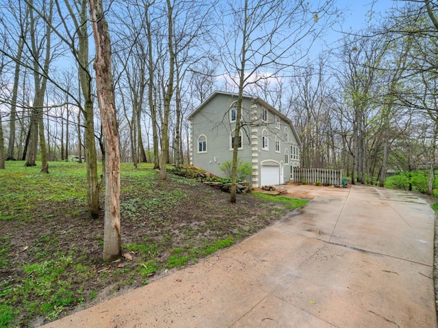 view of side of home featuring stucco siding, concrete driveway, and a garage