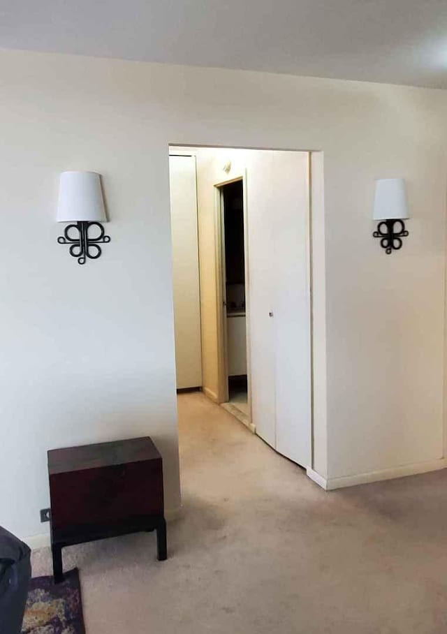 hallway featuring light carpet and baseboards