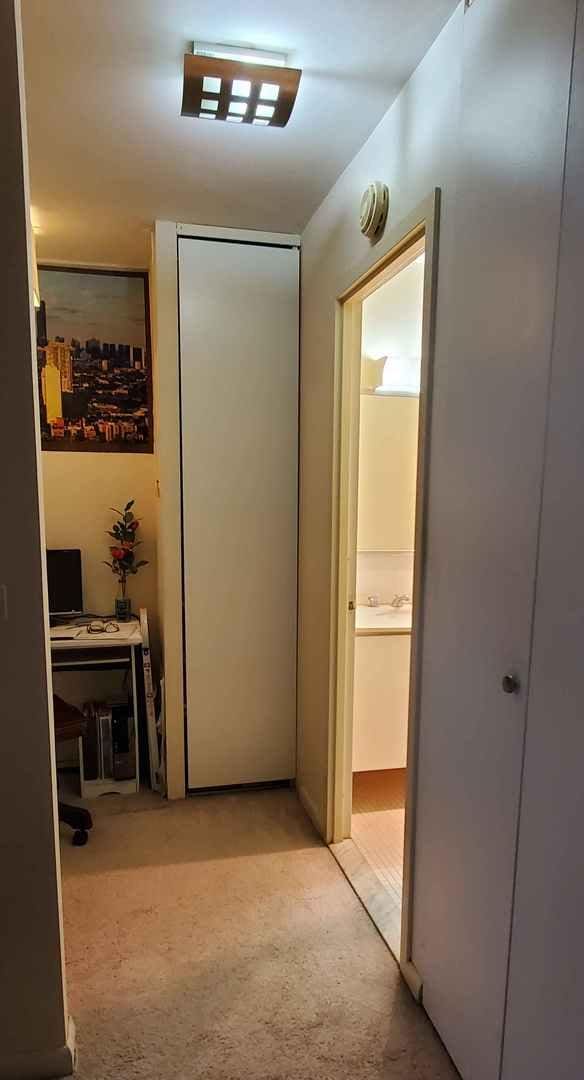 hall featuring light colored carpet and a desk