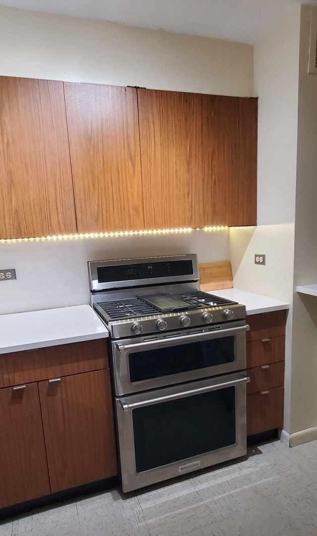 kitchen with range with two ovens, light countertops, baseboards, modern cabinets, and brown cabinets