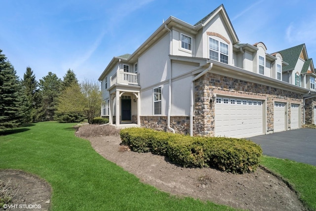 view of side of property with stone siding, stucco siding, a balcony, a yard, and driveway