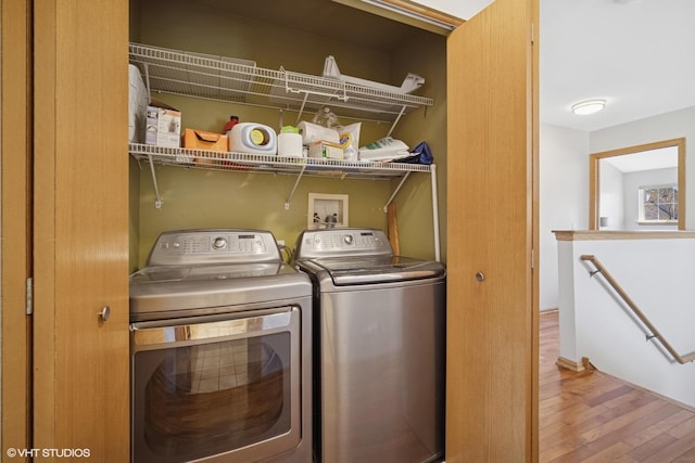 clothes washing area with laundry area, washing machine and dryer, and wood finished floors
