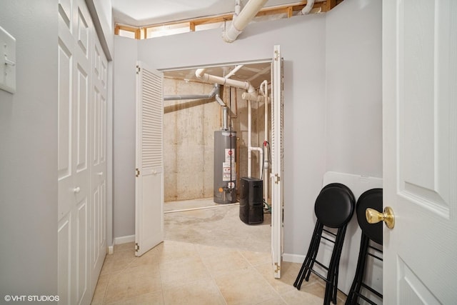 interior space featuring baseboards, tile patterned floors, and gas water heater