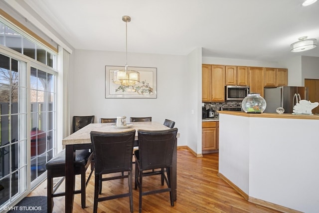 dining room featuring baseboards, a chandelier, and light wood-type flooring