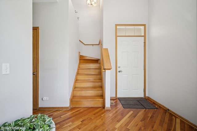 foyer entrance with stairway, baseboards, and light wood finished floors