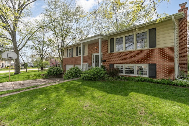 split foyer home featuring an attached garage, a front lawn, brick siding, a chimney, and concrete driveway