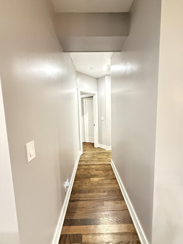 hall with baseboards and wood finished floors