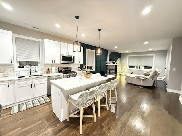 kitchen with tasteful backsplash, stainless steel appliances, a sink, white cabinetry, and visible vents