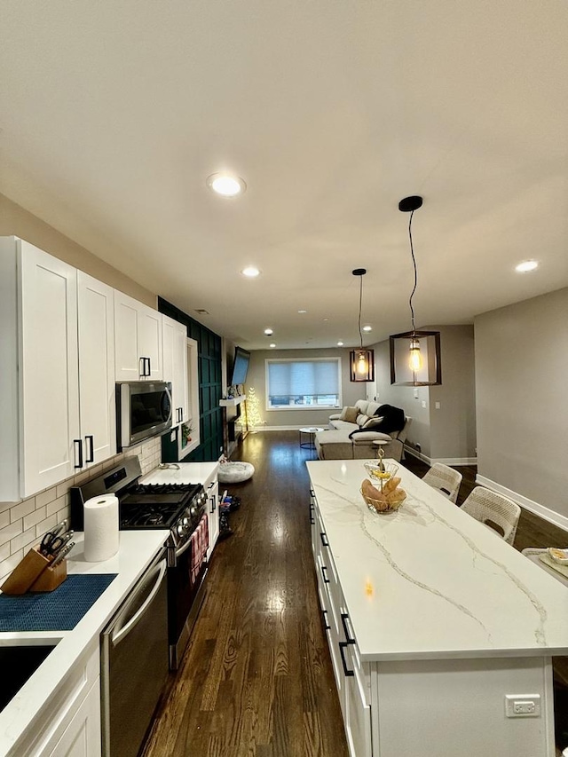 kitchen featuring dark wood-style flooring, a center island, white cabinetry, appliances with stainless steel finishes, and open floor plan