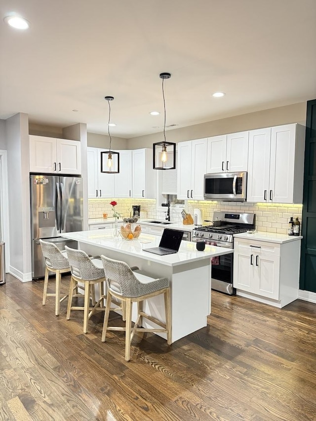 kitchen featuring stainless steel appliances, a kitchen breakfast bar, backsplash, a kitchen island, and light countertops