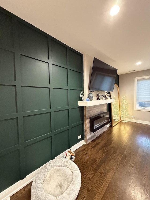 living room with a glass covered fireplace, recessed lighting, dark wood finished floors, and baseboards
