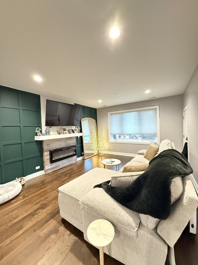 living room featuring recessed lighting, wood finished floors, and a glass covered fireplace