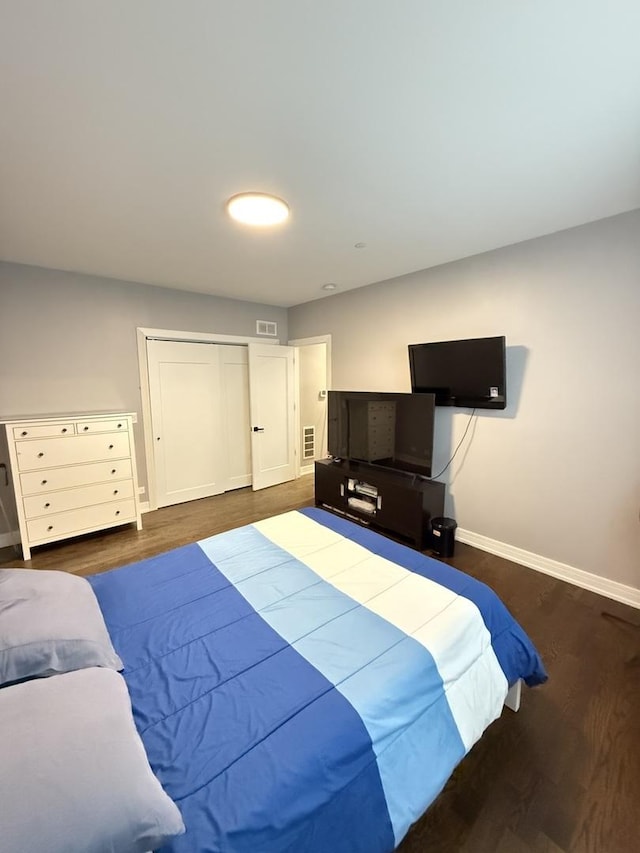 bedroom featuring wood finished floors, a closet, visible vents, and baseboards
