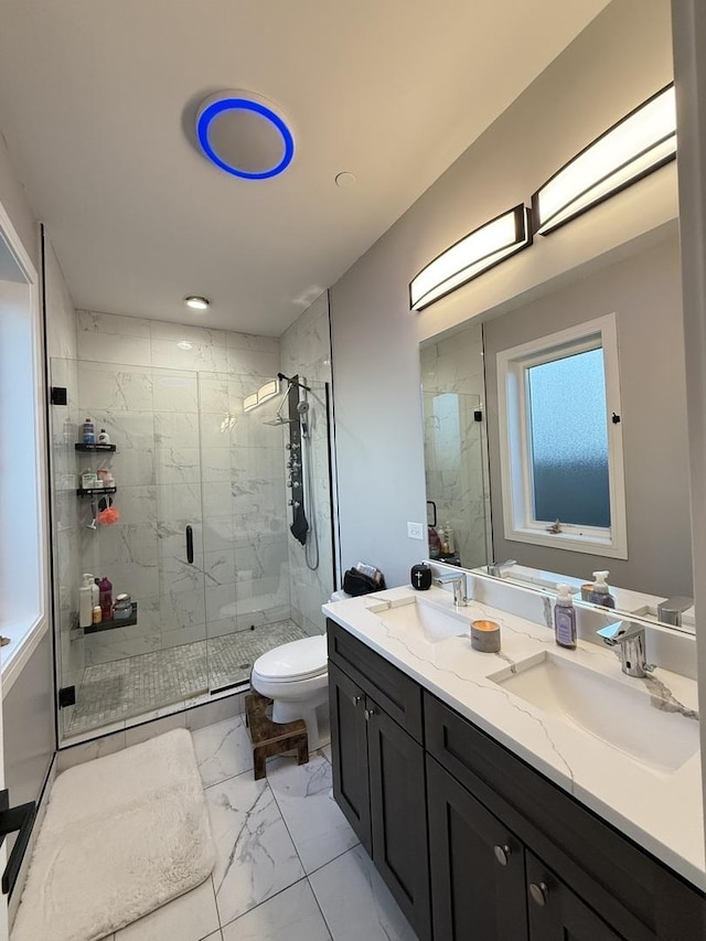 bathroom featuring double vanity, toilet, marble finish floor, and a sink