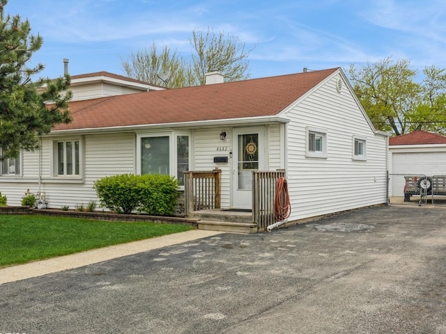 ranch-style house featuring roof with shingles, a chimney, a garage, and aphalt driveway