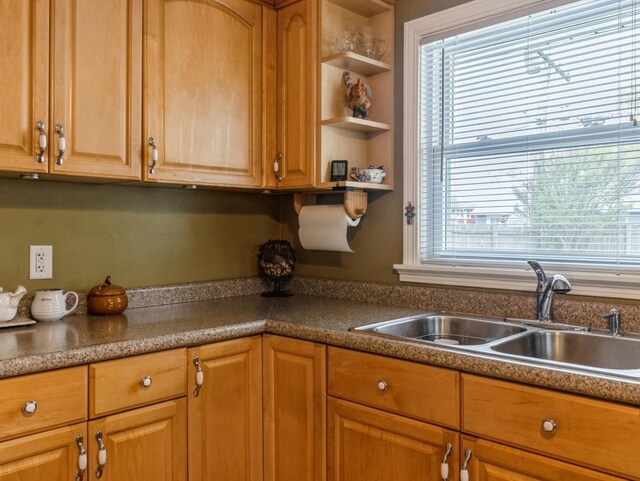 kitchen with open shelves, brown cabinetry, and a sink