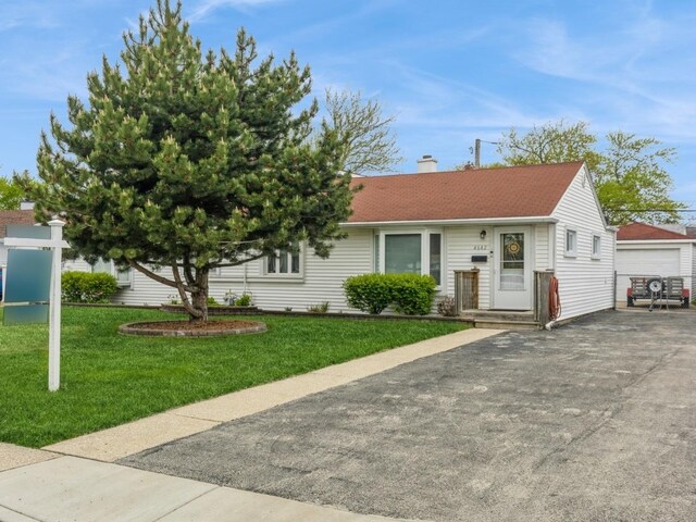 view of front of home with a detached garage, an outdoor structure, a chimney, and a front yard