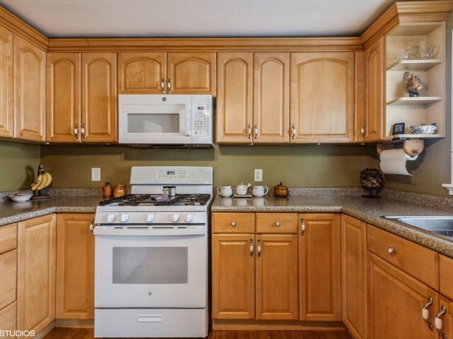 kitchen with dark wood-style flooring, dark countertops, open shelves, a sink, and white appliances