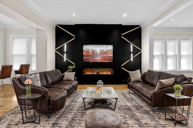 living area with a fireplace, wood finished floors, recessed lighting, and ornamental molding