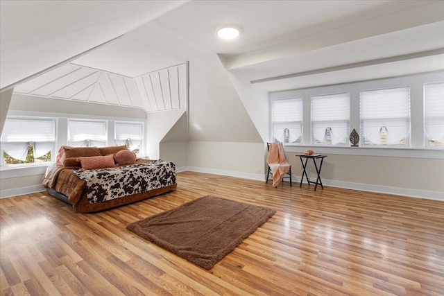bedroom with multiple windows, wood finished floors, and baseboards