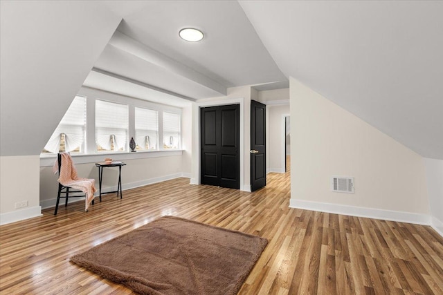 bonus room with lofted ceiling, wood finished floors, visible vents, and baseboards