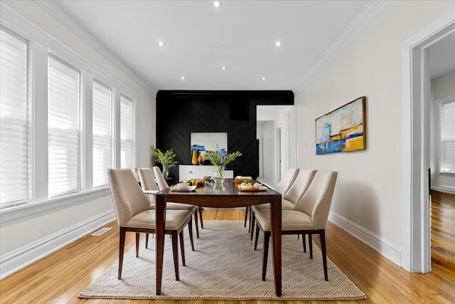dining room with baseboards, visible vents, ornamental molding, and light wood-style floors