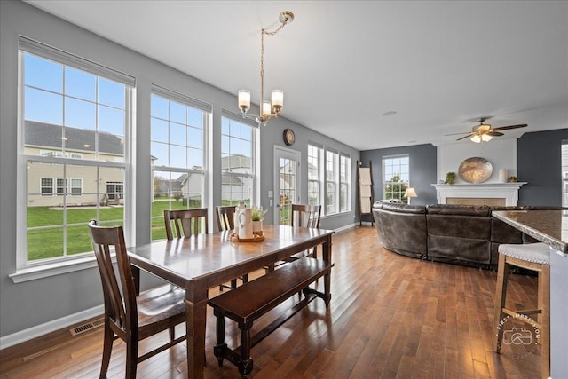dining area with a fireplace, baseboards, visible vents, and hardwood / wood-style floors