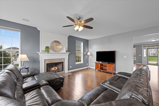 living area featuring ceiling fan, wood finished floors, a healthy amount of sunlight, and a fireplace