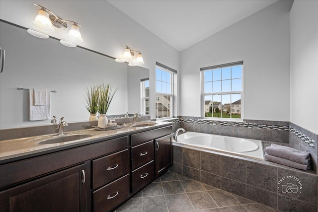 full bath with a sink, double vanity, vaulted ceiling, and a garden tub