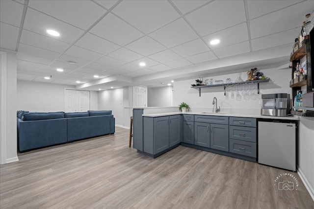 kitchen with open shelves, a sink, light wood finished floors, and fridge