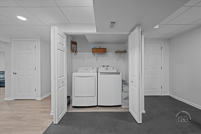 laundry area with laundry area, visible vents, washing machine and dryer, wood finished floors, and baseboards